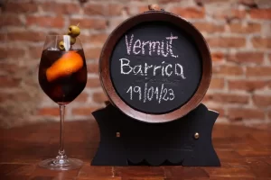 Copa de Vermut Barrica con naranja y aceitunas junto al barril de Leinerhaus