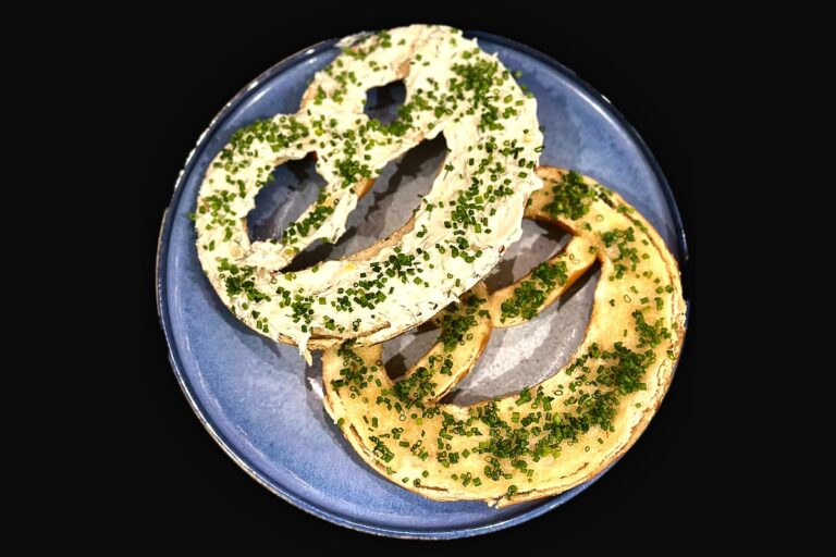 Wunderbretzel abierto en dos con crema de hierbas y mantequilla